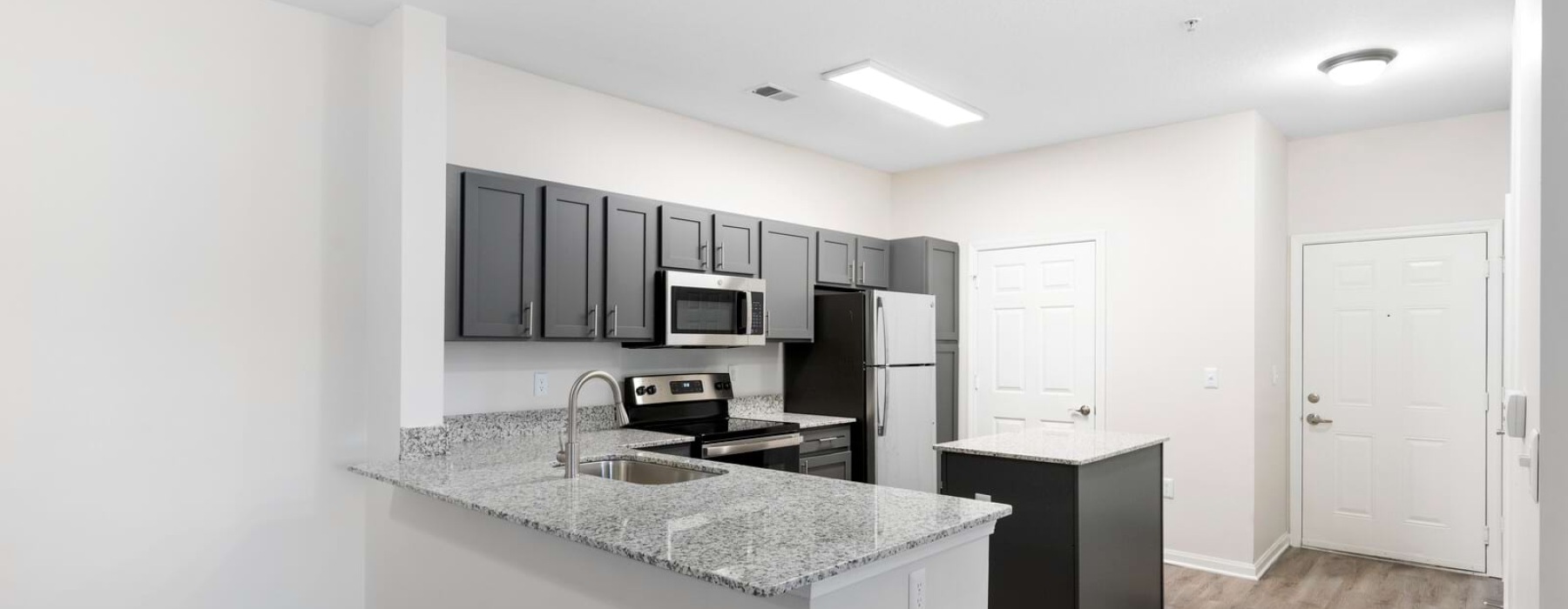 kitchen with grey cabinets, stainless steel appliances, and granite countertops