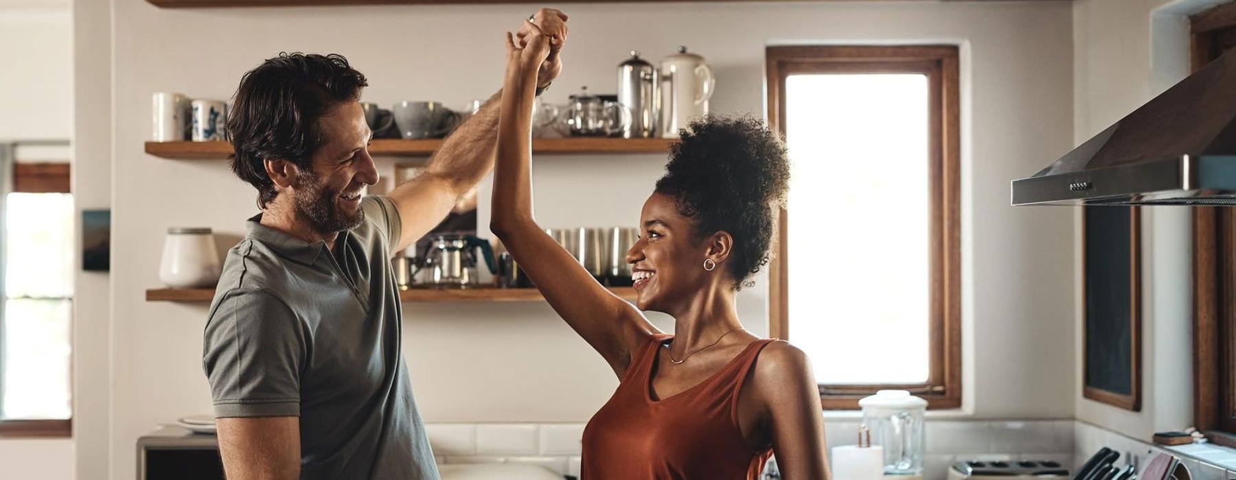 a man and a woman dance in well lit kitchen
