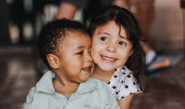 A perfect fit for the whole family little girl hugs baby boy as they sit on a floor
