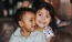 little girl hugs baby boy as they sit on a floor